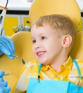 a toddler sits smiling at the dentist at a pediatric dentist appointment