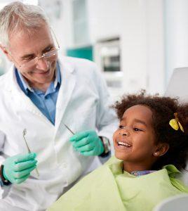 a young girl smiles and laughs while a dentist smiles at her