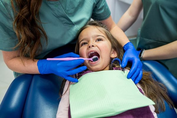 a young girl gets her teeth cleaned during a pediatric dentist appointment
