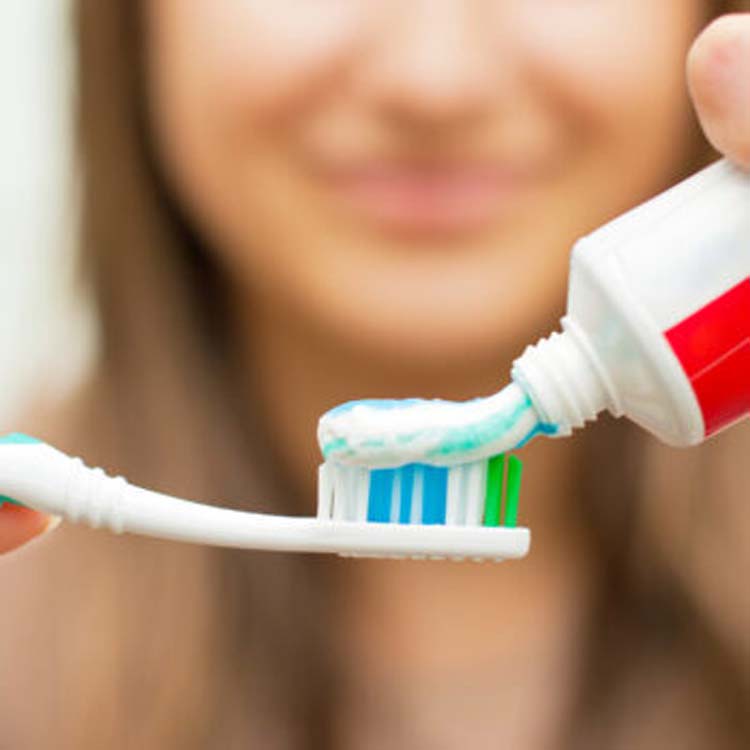a woman adds fluoride toothpaste to her toothbrush